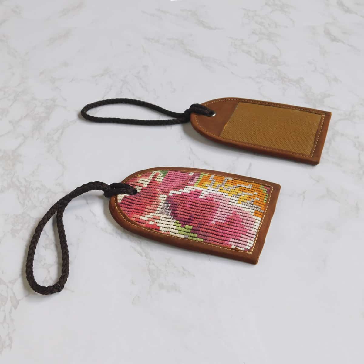 front and back of a handmade fabric luggage tags with pink brocade and a leather backing