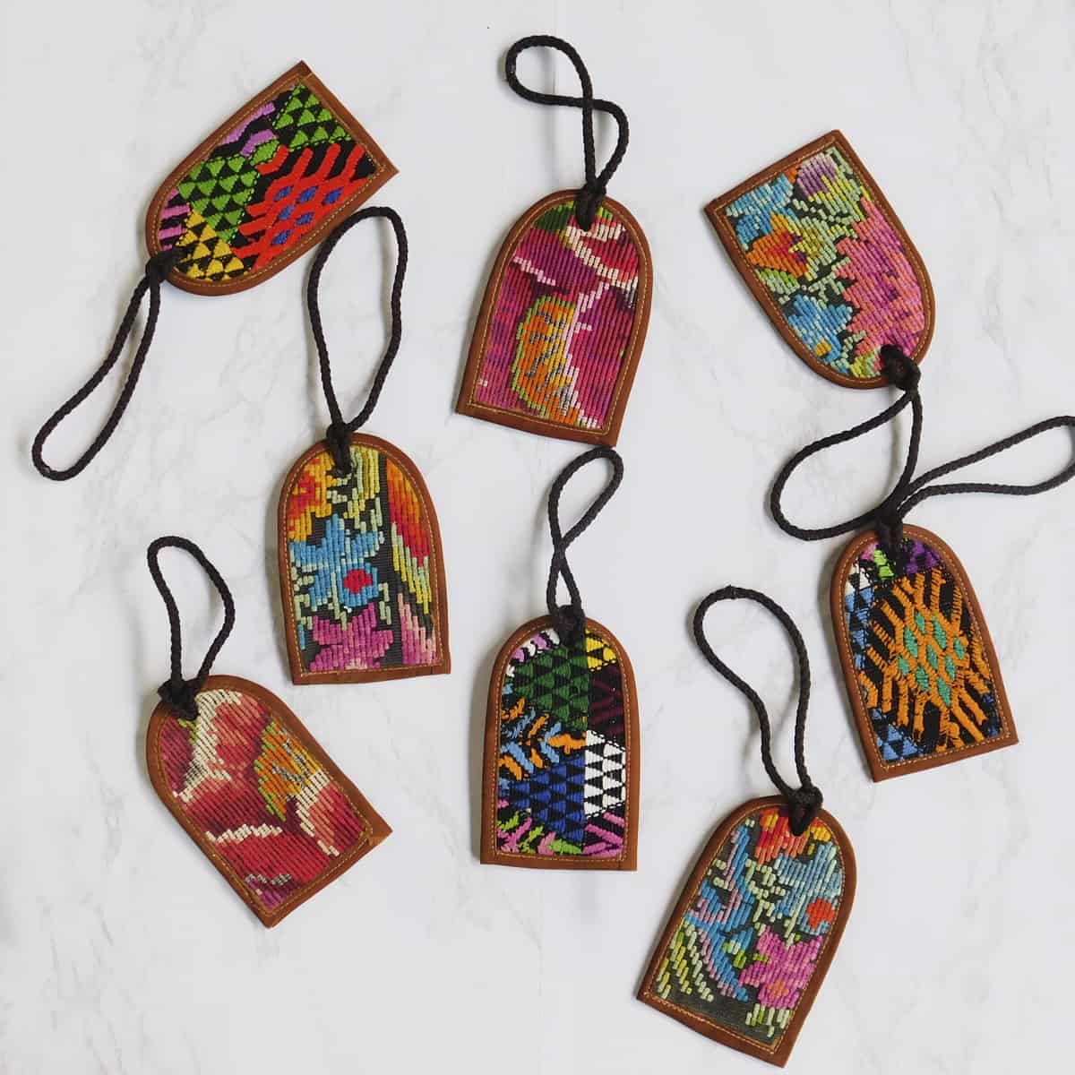 A set of eight handmade leather luggage tags with a variety of colorful huipil fabrics