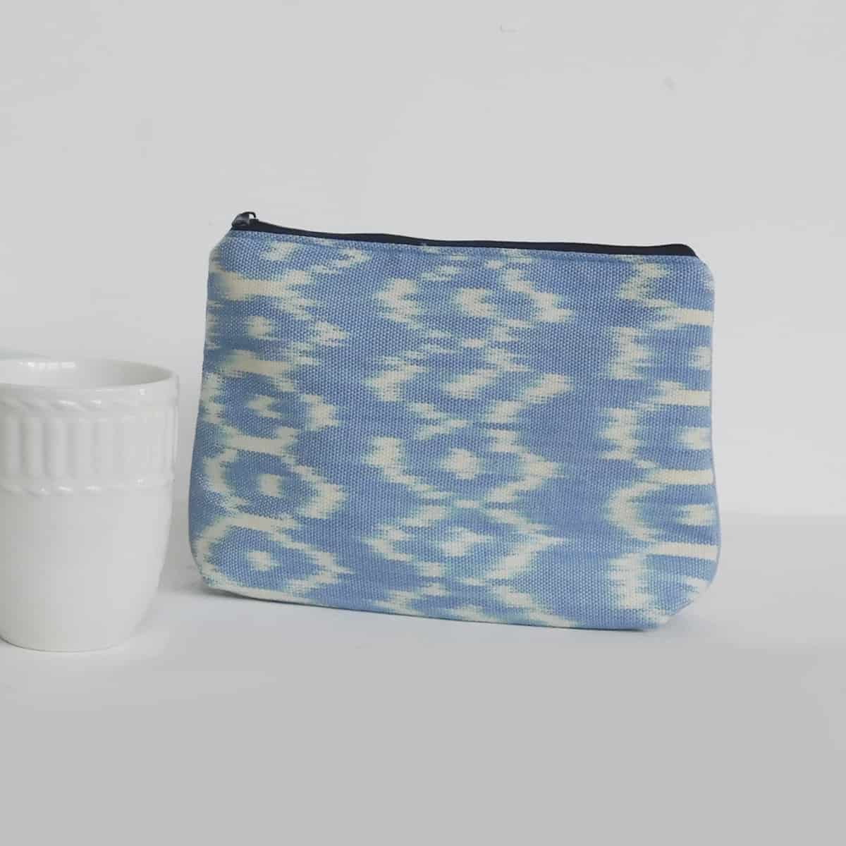 luxury cosmetic bag in light blue ikat design with a zipper on a white background