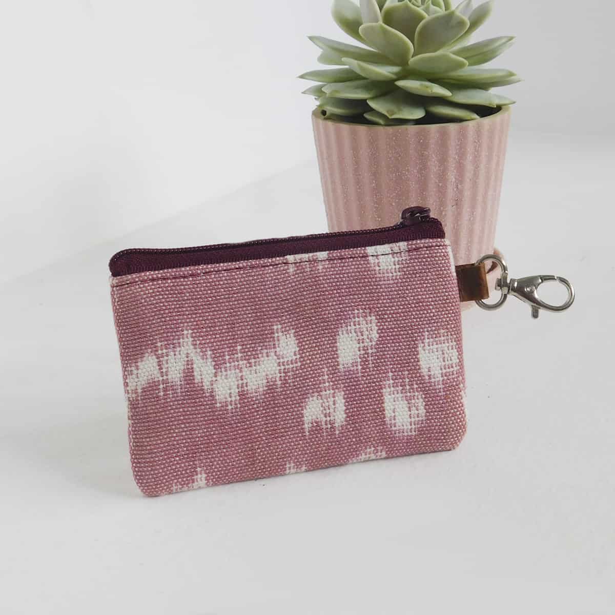 a handmade pink card holder wallet featuring an eggplant colored zipper enclosure