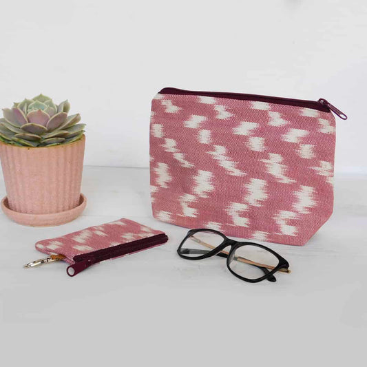 handmade makeup bag and card holder wallet in pink with ikat design on a white background with glasses and succulent next to them