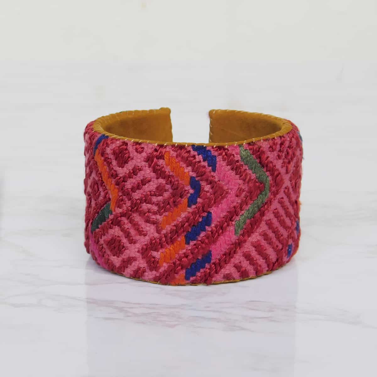 red cuff bracelet with hand woven huipil fabric on a leather backing