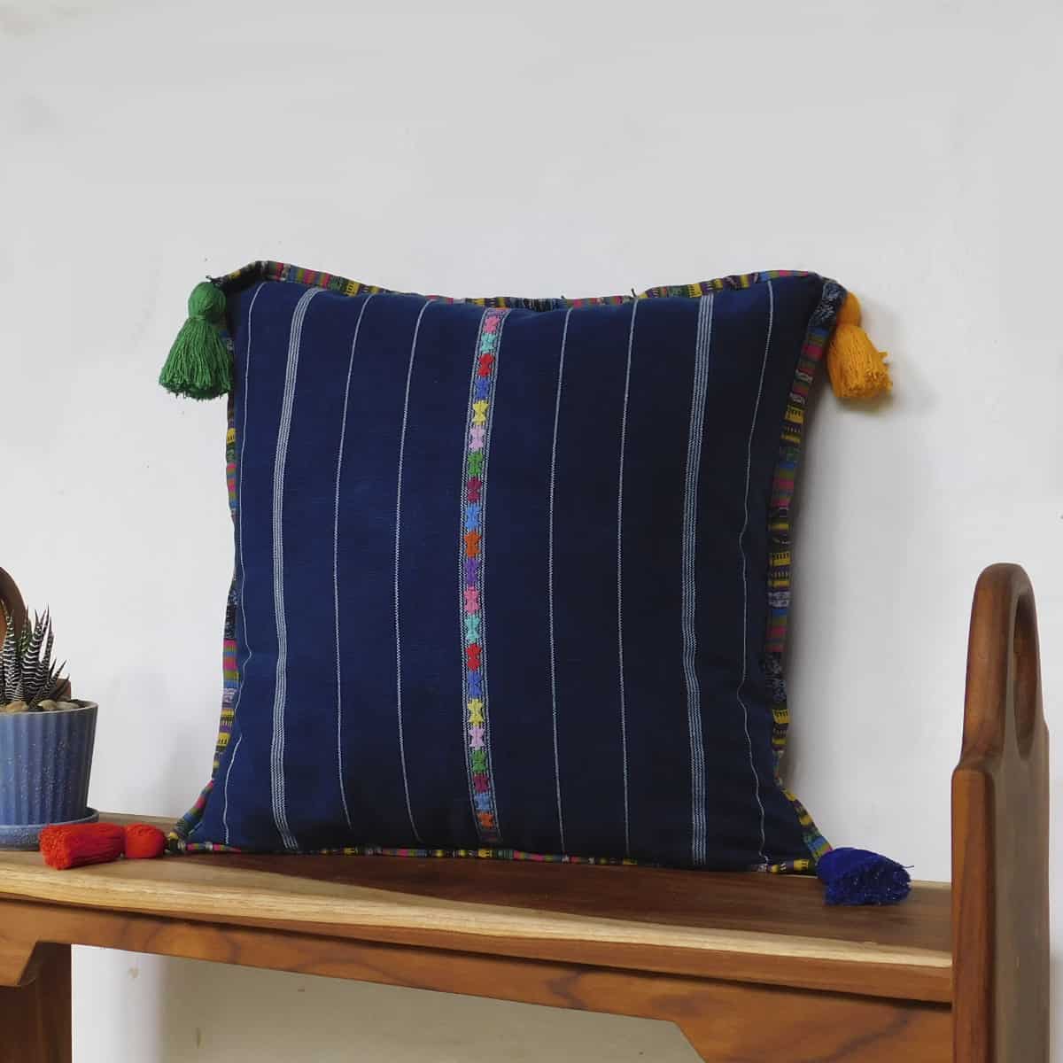 luxury throw pillow made of Guatemalan corte material on a wooden bench
