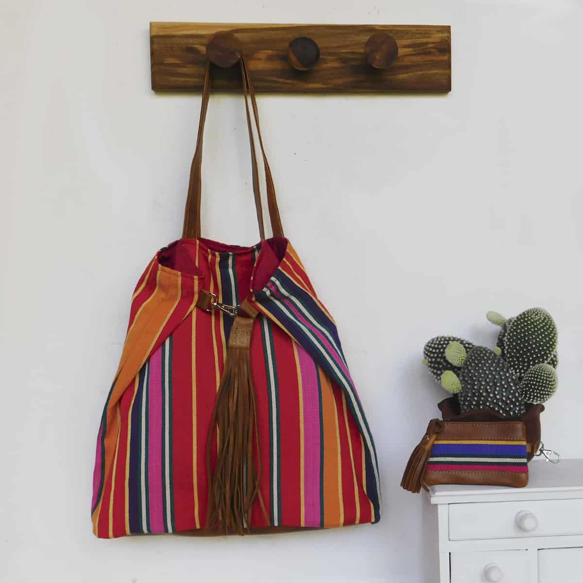 striped red tote bag with leather handles hanging next to a matching red coin purse with zipper enclosure.  