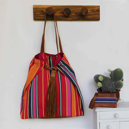 striped red tote bag with leather handles hanging next to a matching red coin purse with zipper enclosure.  