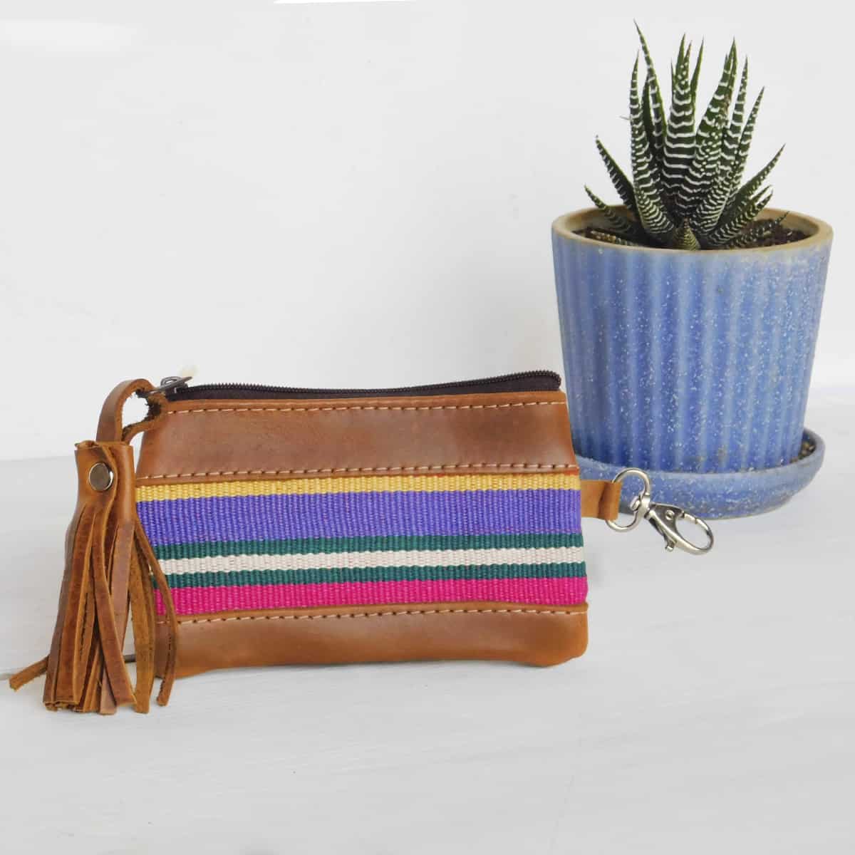 close up of a leather coin purse with zipper. this striped red coin purse also features a decorative leather tassel and lobster clasp for keys