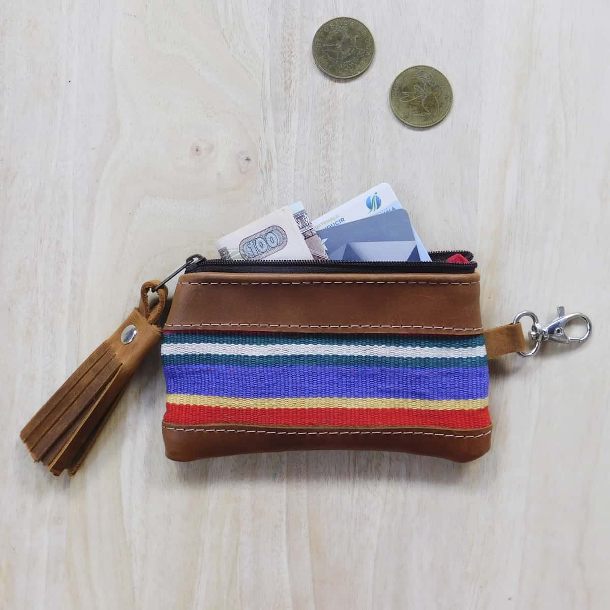 a striped red coin purse with leather details with folded money and credit cards partially placed inside