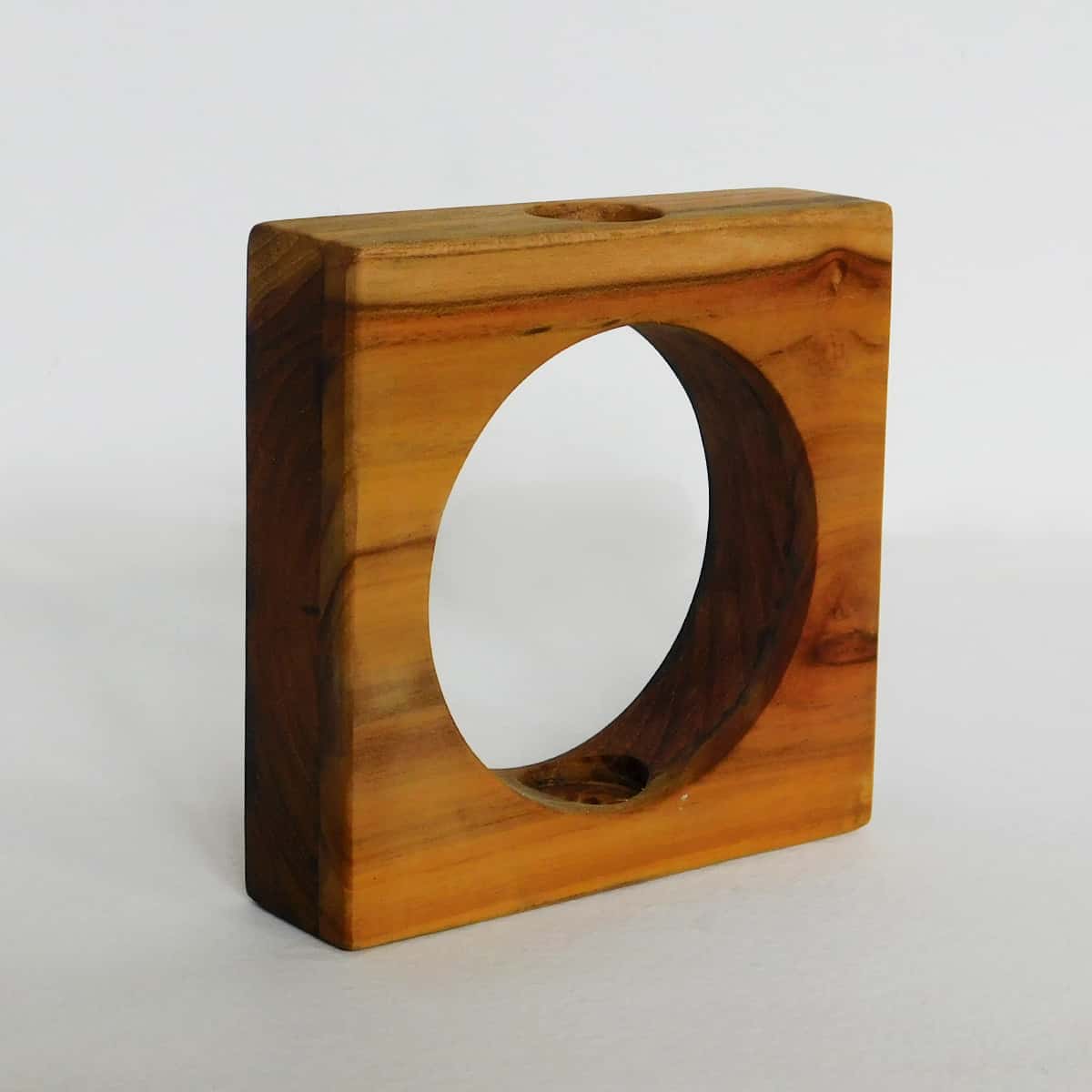 a square teak frame with circular cutout seen from the side. used for small glass tubes for flowers