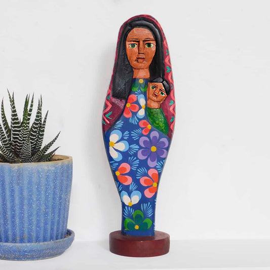 A wooden virgin mary statue made of pine and hand painted in Guatemala. Mary's robe has a floral motif and she is holding Baby Jesus.