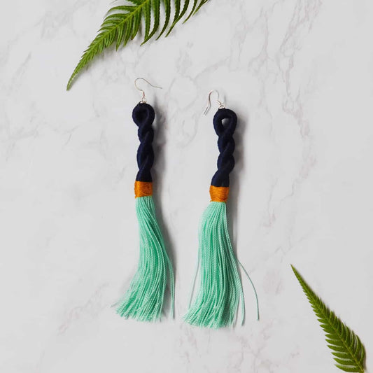 aqua tassel earrings with a cotton navy blue spiral and gold-colored strip onwhite marble