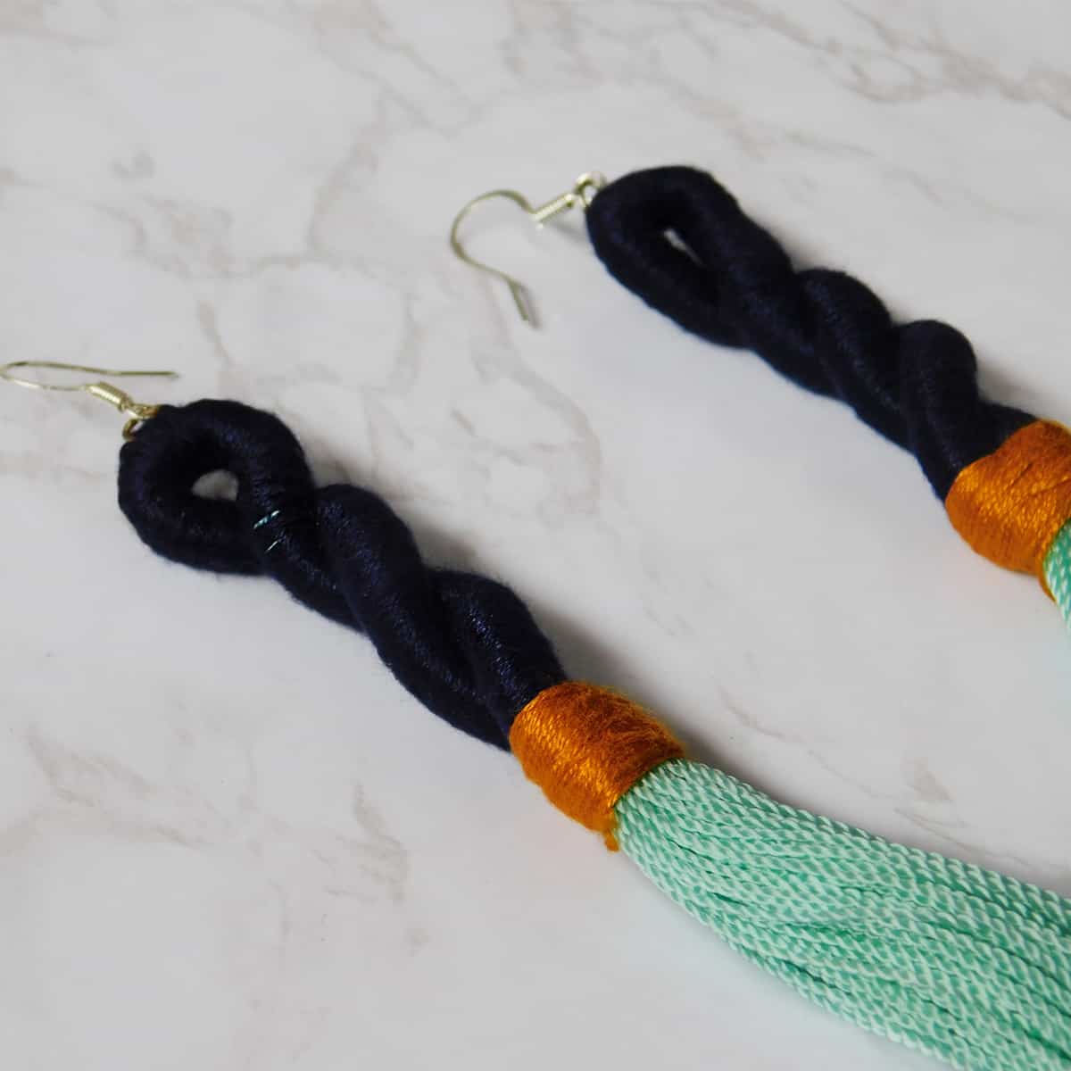 close up shot of navy blue spiral on colorful earrings with aqua tassels